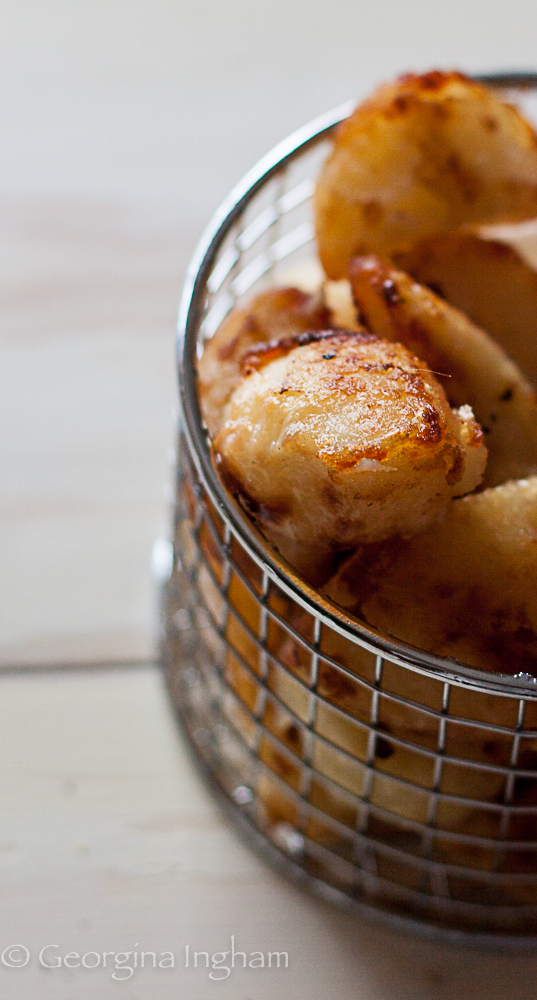 Close-up of crispy golden roast potatoes in a wire serving basket.